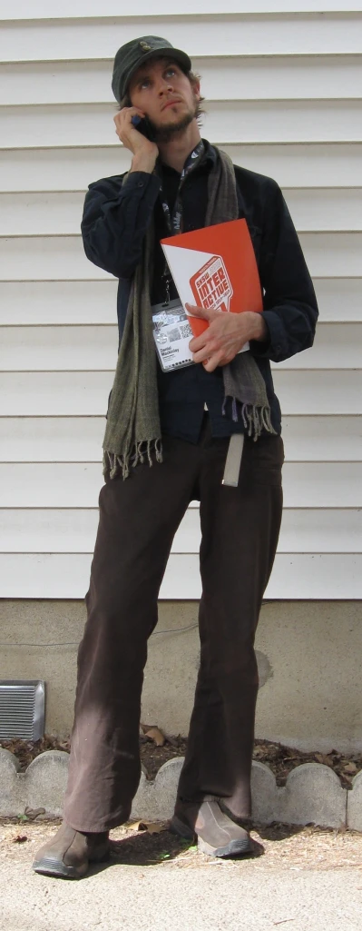 man wearing brown pants and scarf talking on a cell phone
