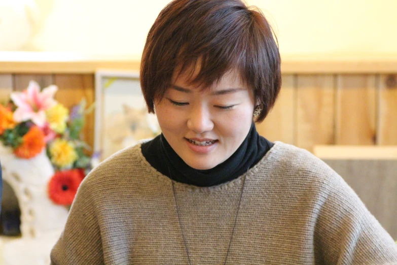 a girl with short hair, wearing a grey sweater