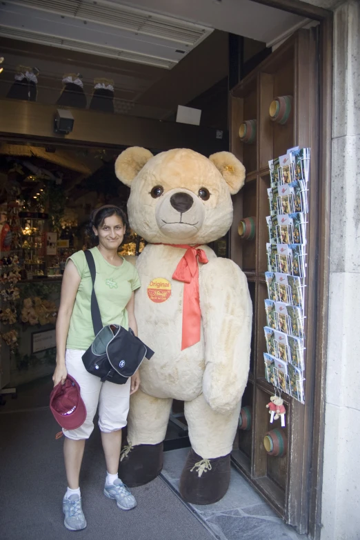 the person is standing next to the big teddy bear