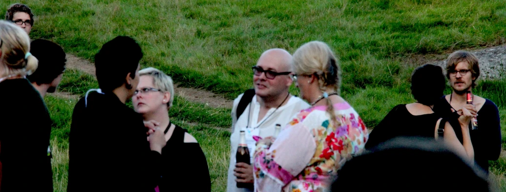 an older man wearing glasses talking to some other men