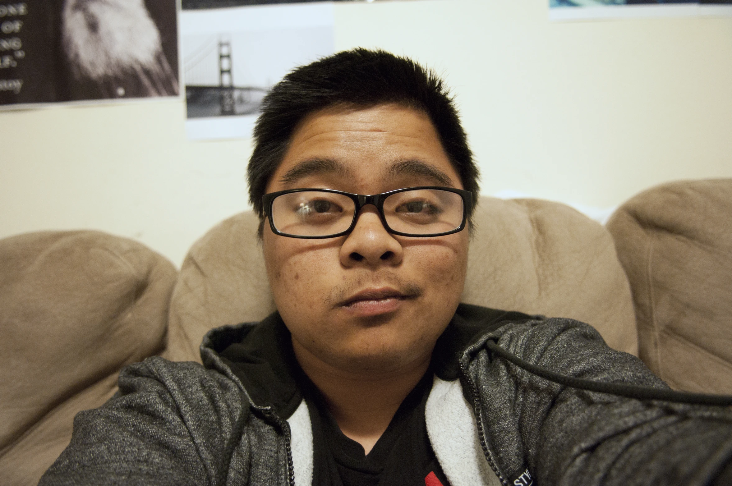 a man wearing glasses while sitting on top of a couch
