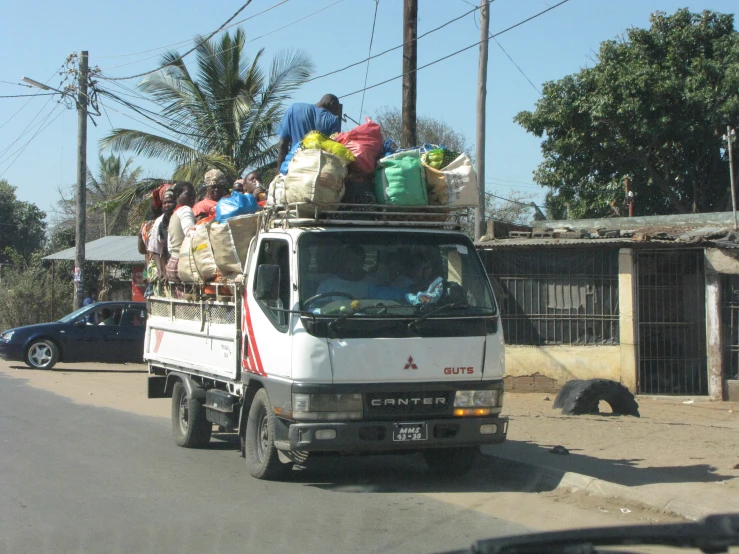 a truck driving down a street carrying a group of people