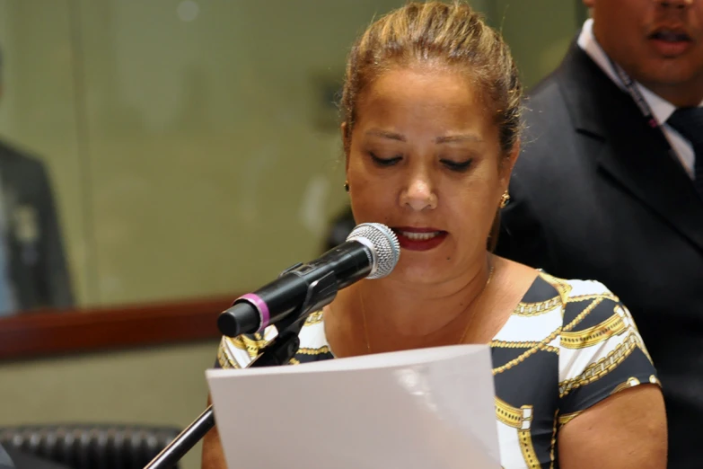 a woman is standing and speaking into a microphone