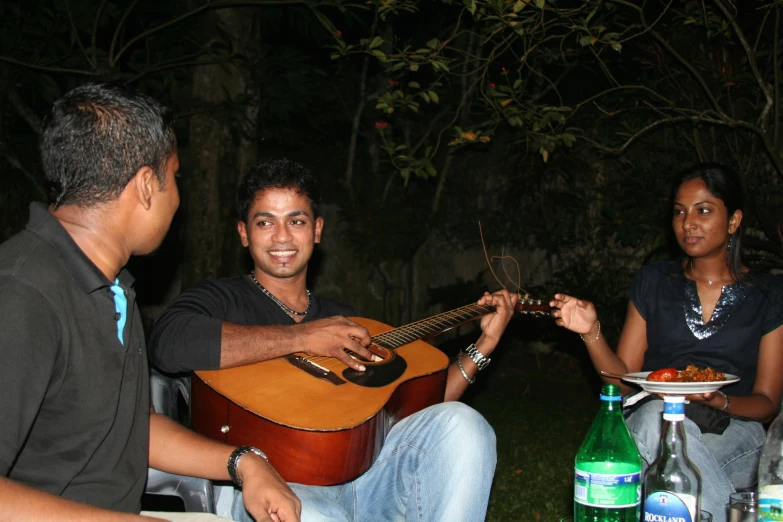 a man holding an acoustic guitar sitting on top of a chair