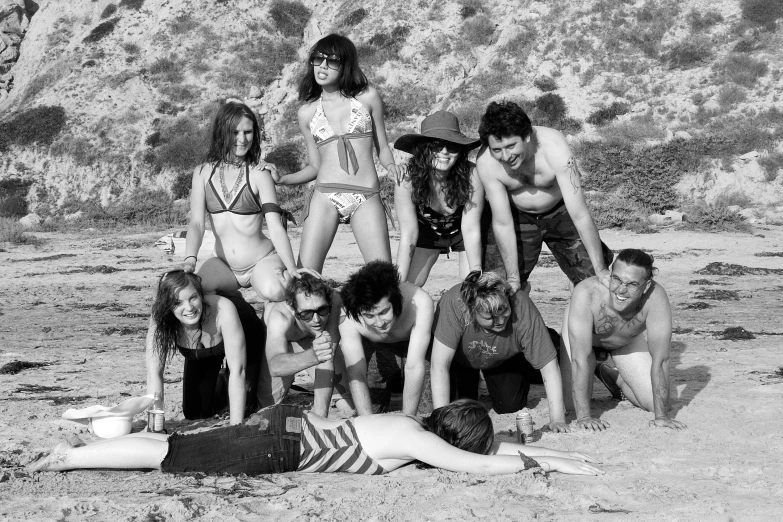 a group of young people are posing on the beach