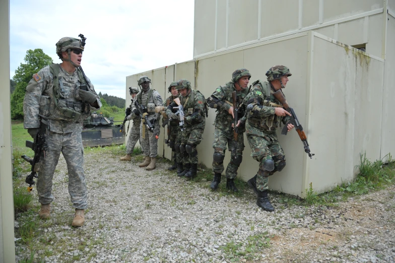 several soldiers are standing by a wall and holding guns