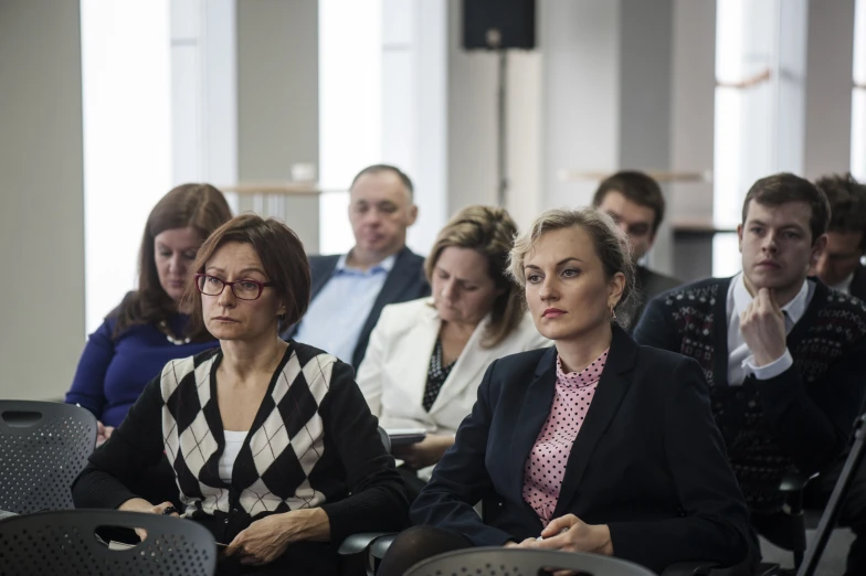 two women at a meeting with people behind them