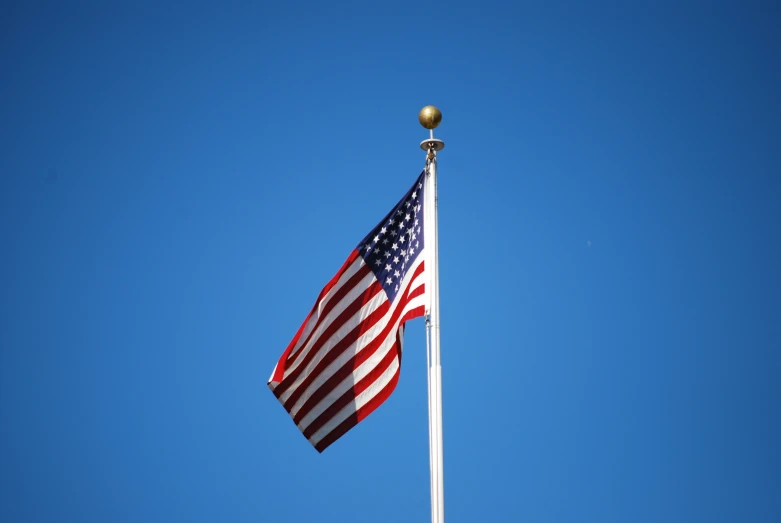 a small flag on top of a pole in the sky