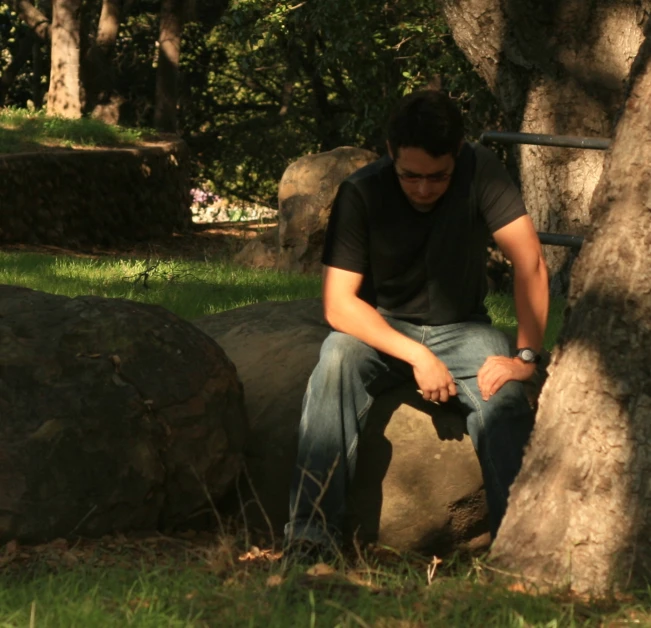 a man is sitting down on rocks with his hands under the knees