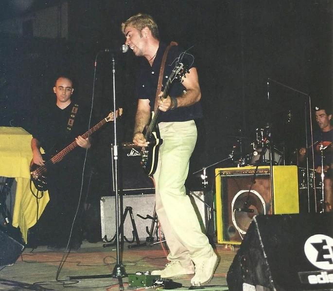 three men singing into microphones in front of microphone equipment