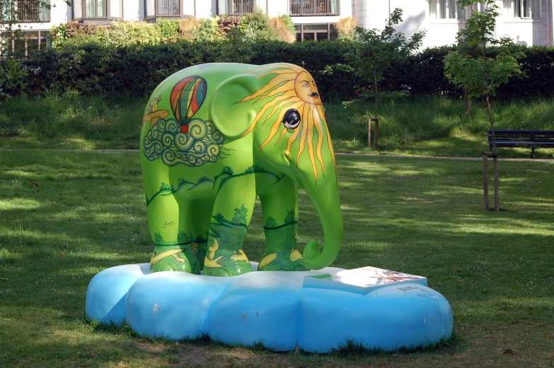 the green elephant stands on two blocks of cement in front of a building