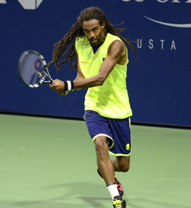 man with dreadlocks playing tennis on a tennis court