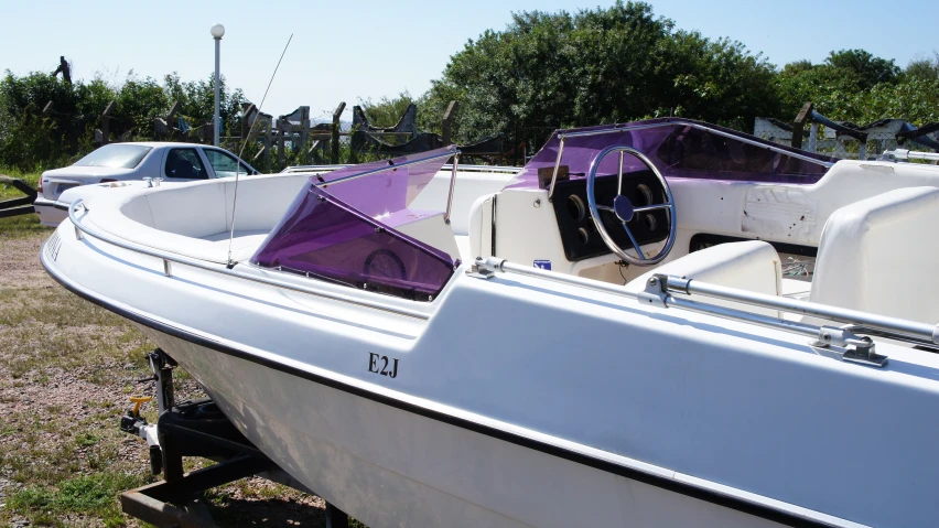 a row of white boats parked in a field next to a forest