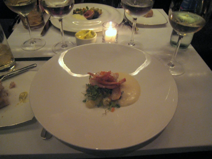 a dinner table with white plates of food and two candles