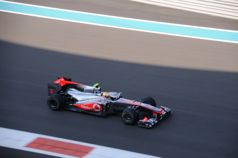 a racing car driving down a track with people watching