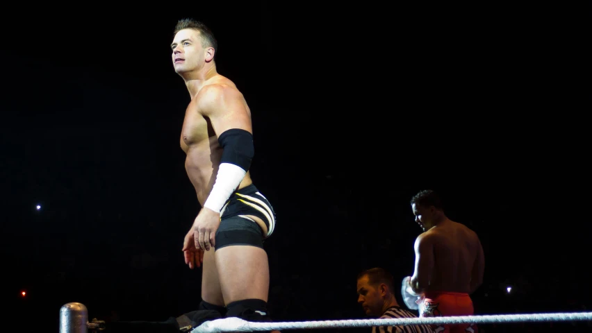 a man standing in a wrestling ring with his hand on the ring