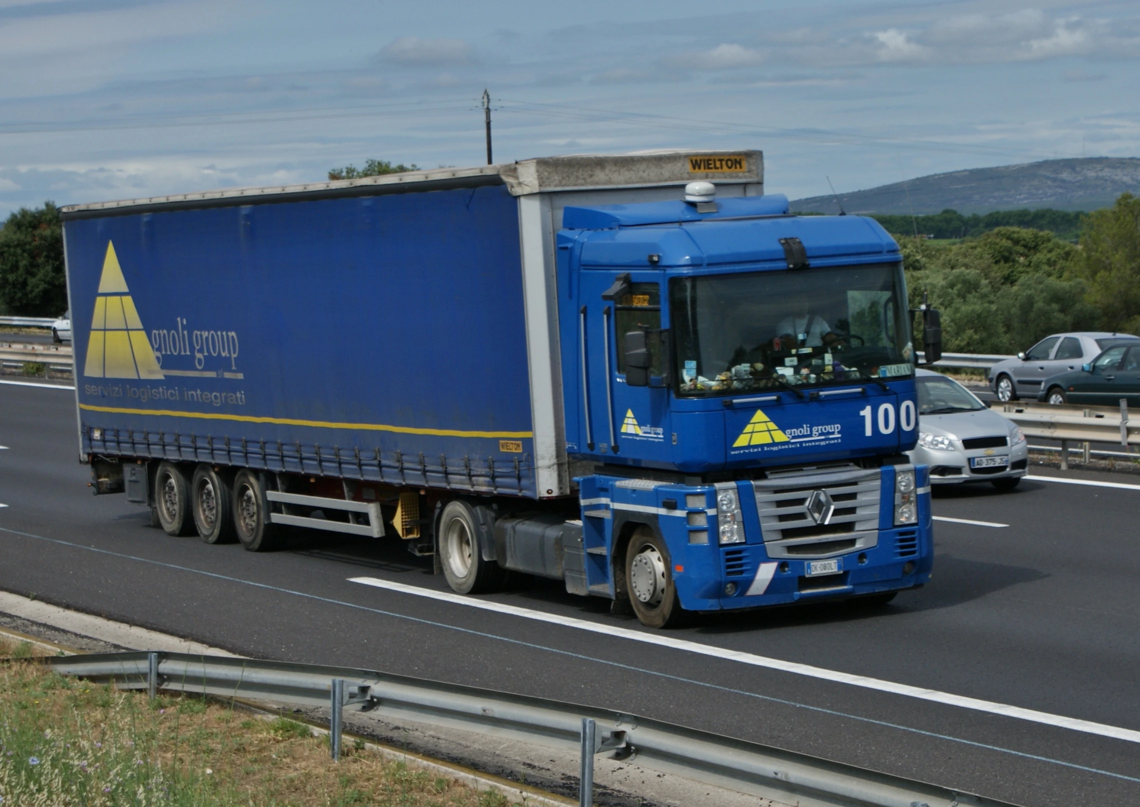 a blue semi trailer hauling equipment along a highway