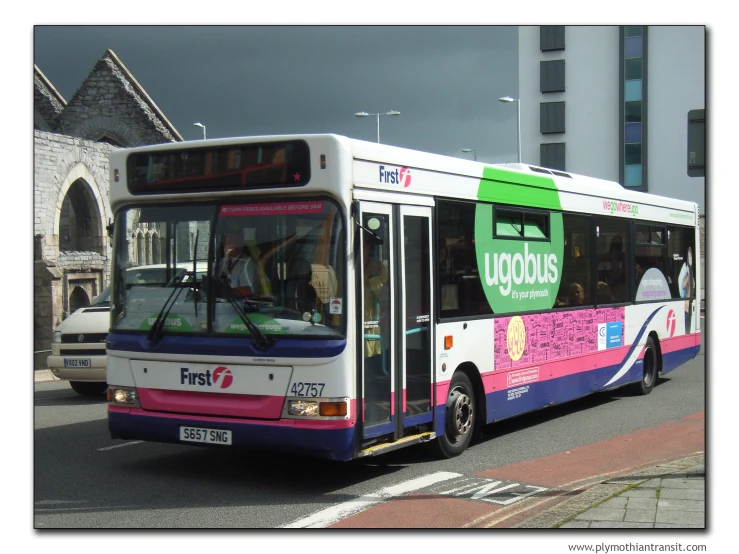 a bus sits parked in a lot next to buildings