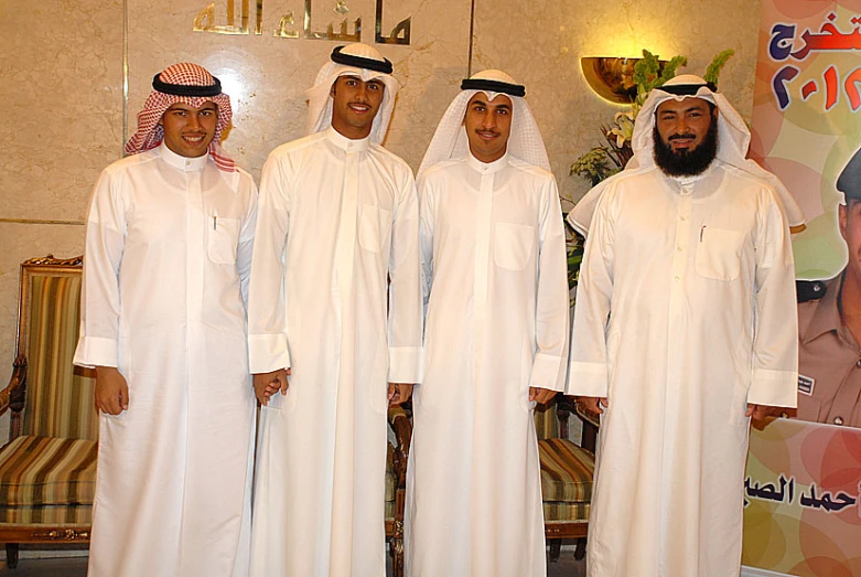 a group of five men standing next to each other in front of a sign