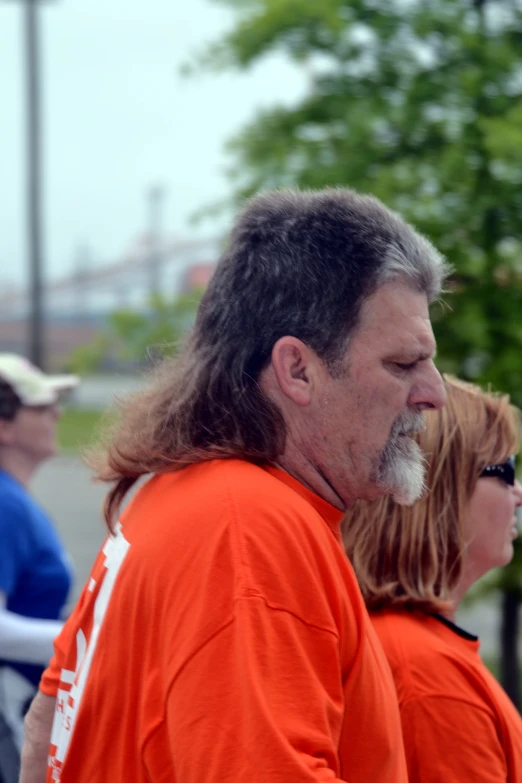 a man with long hair, wearing orange and white