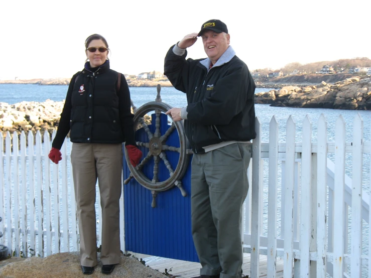 a man and woman stand near a white picket fence