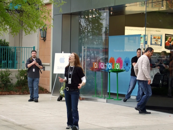 two people on a sidewalk standing behind a sign with the word google in it