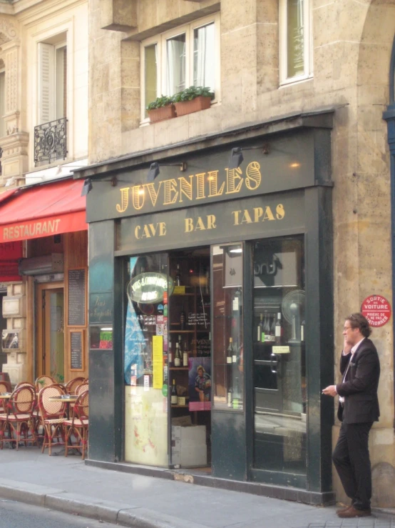 a man standing next to a shop front next to a sidewalk