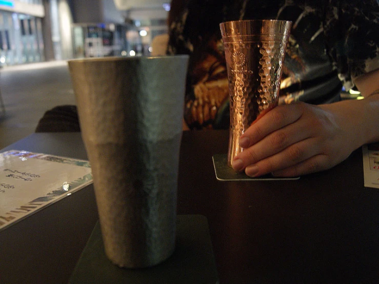 a person holding a tall cup that has a gold colored rim