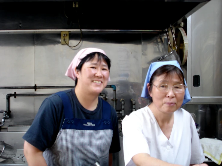 two women standing together in front of a kitchen