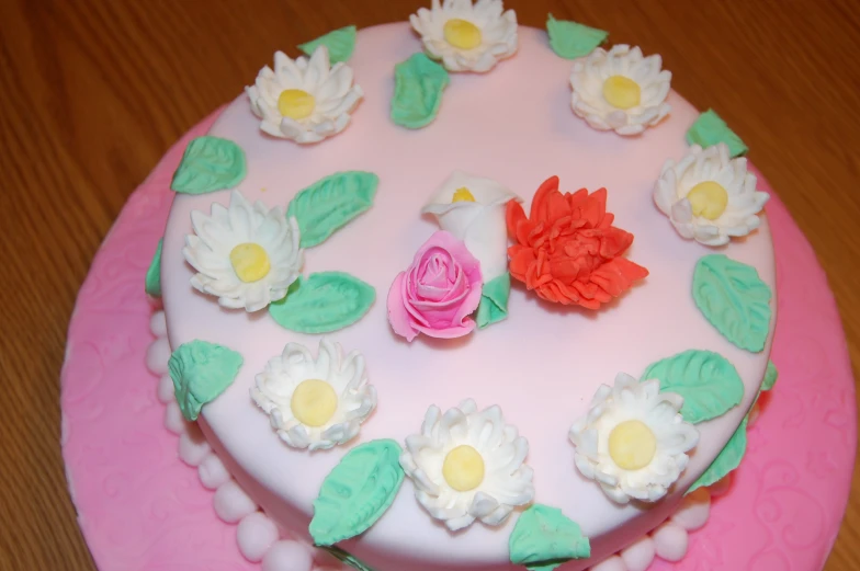 a pink cake with flowers on it and a rose in the middle