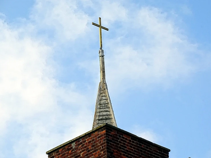 a view from the bottom of a brick church steeple and a cross in the middle of it