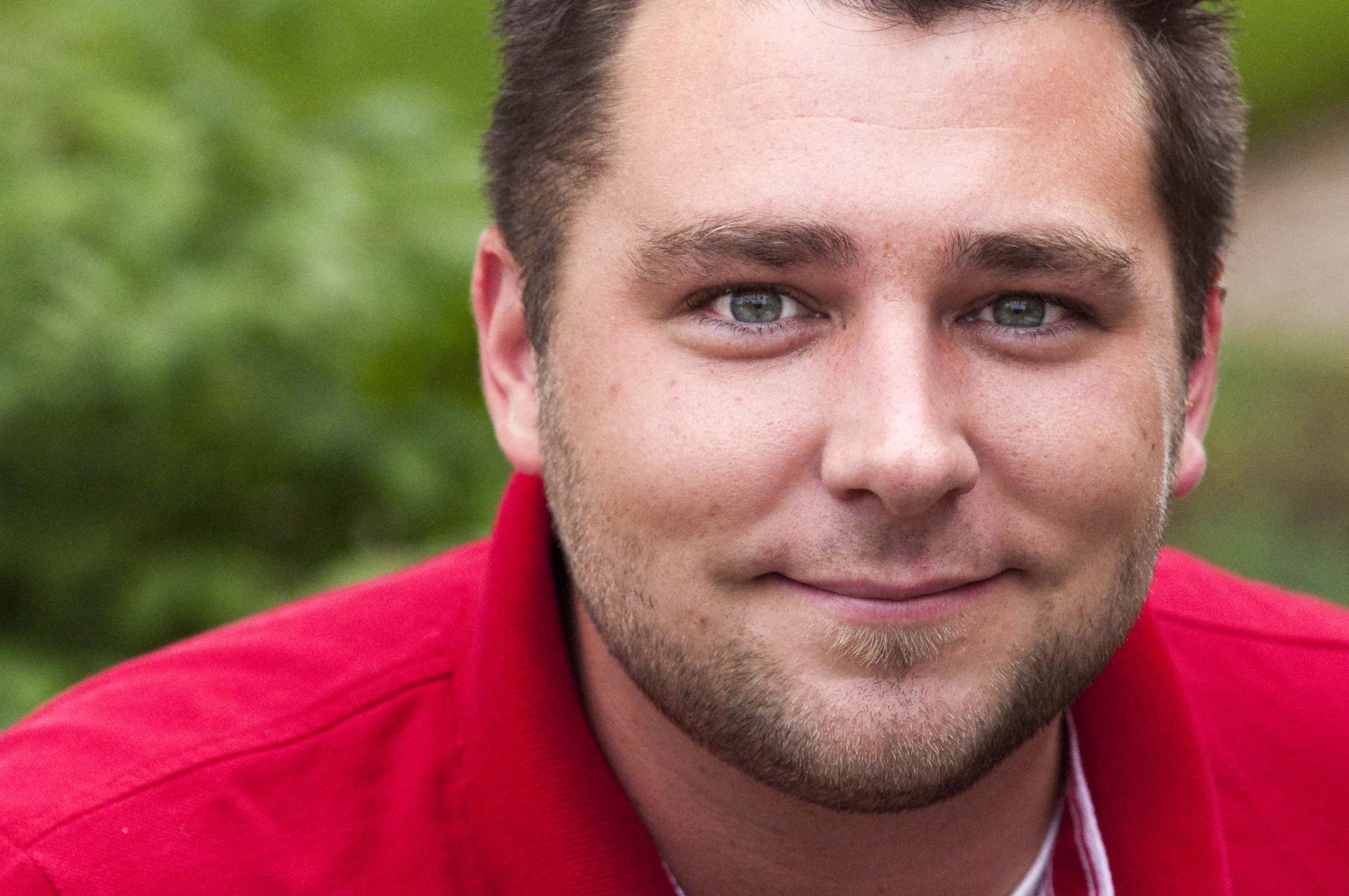 a man with short hair wearing a red shirt