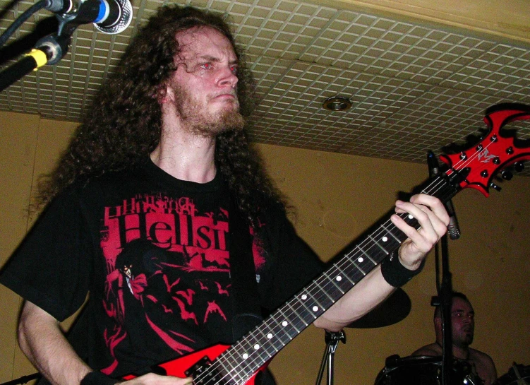 a man with long hair is holding an electric guitar