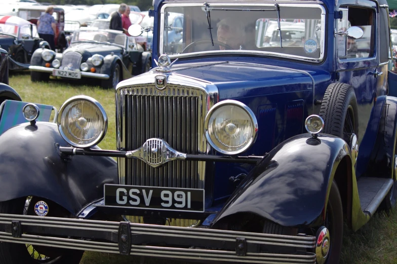 a number of classic cars parked in the grass