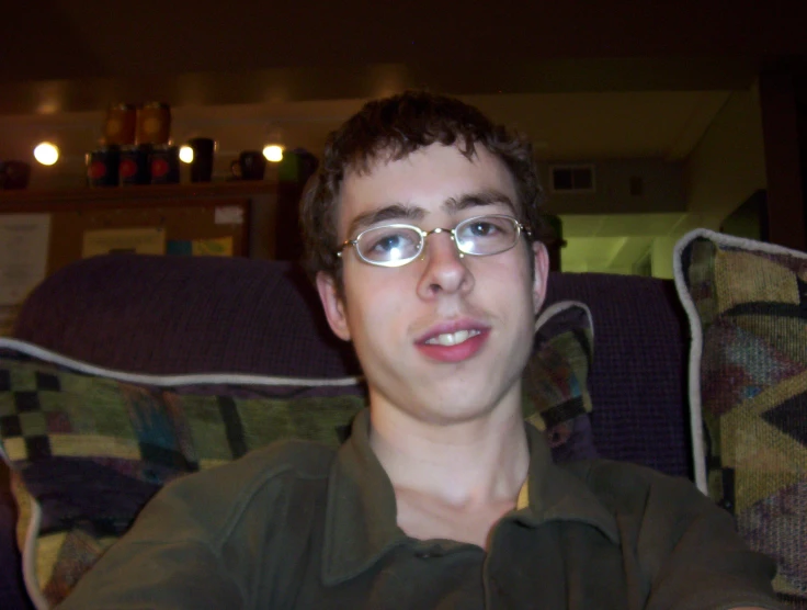 a young man wearing glasses and staring at the camera