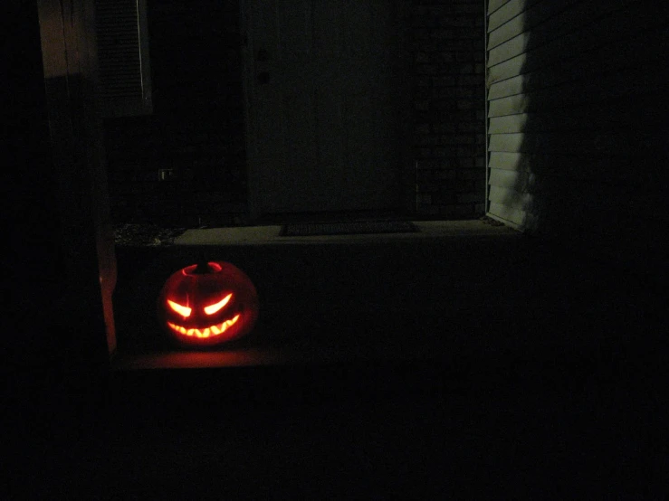 the scary face of an illuminated pumpkin in front of a doorway
