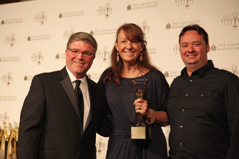 a man and two women pose for a po with an award