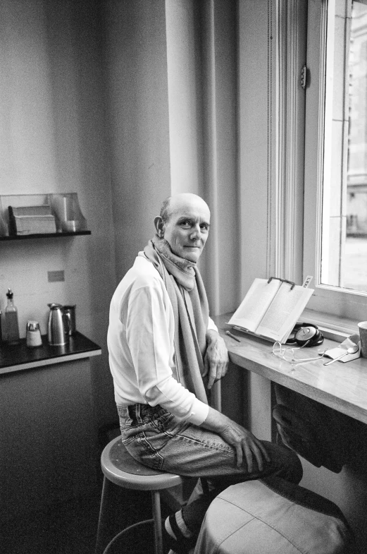 a man wearing glasses sits at his desk in the corner of the room