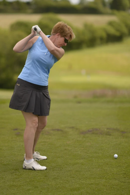 a lady hitting a golf ball on a tee
