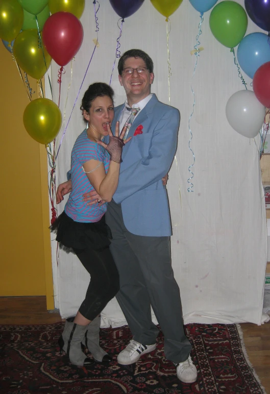 a man and a woman standing under balloons in front of a backdrop