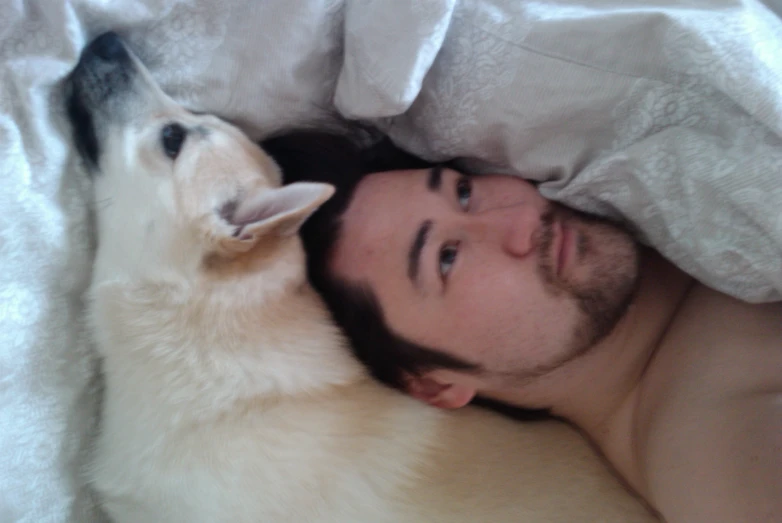 a man and a white dog lying down together