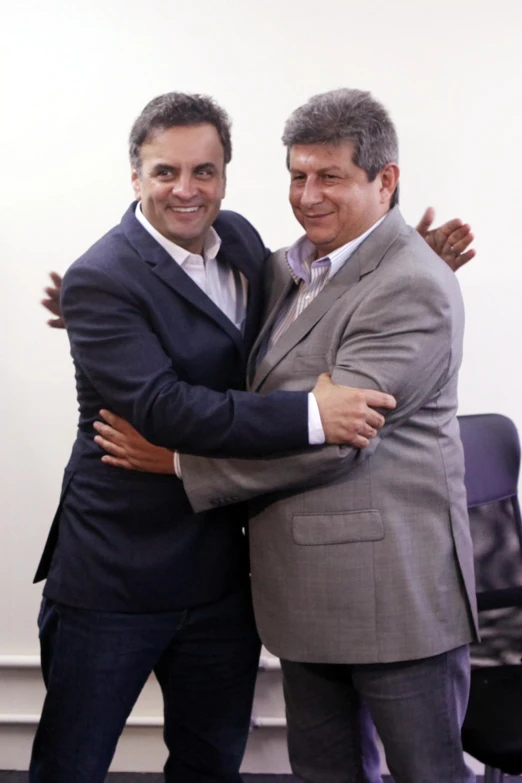 two men hugging while one holds his arm around the other