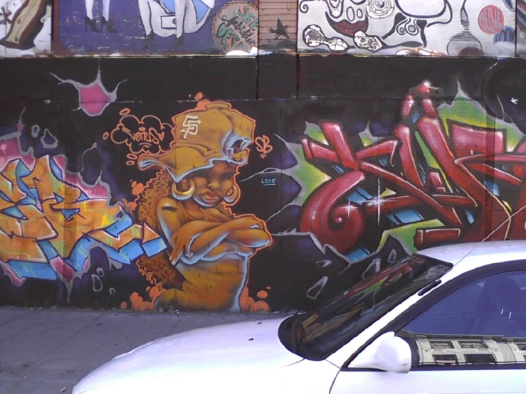 a white car parked next to a wall with graffiti on it