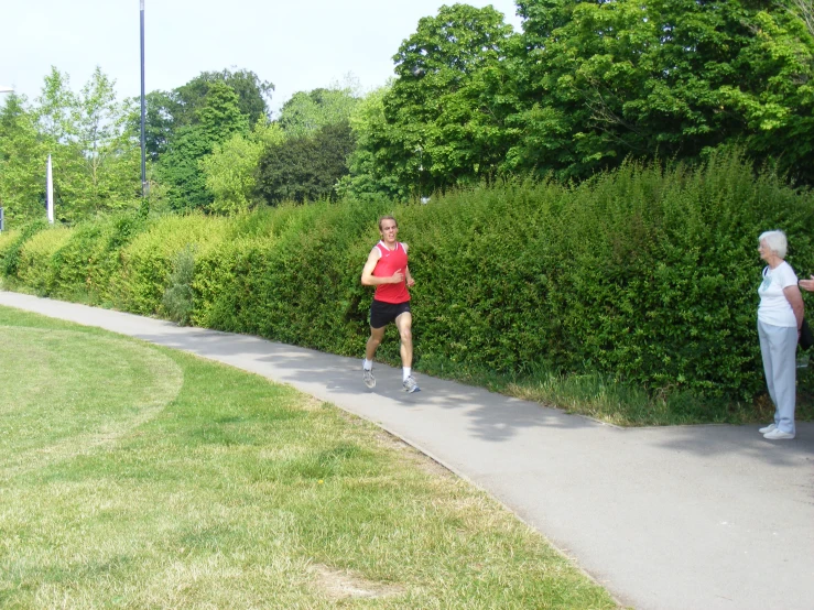 two women running in a park between tall green bushes