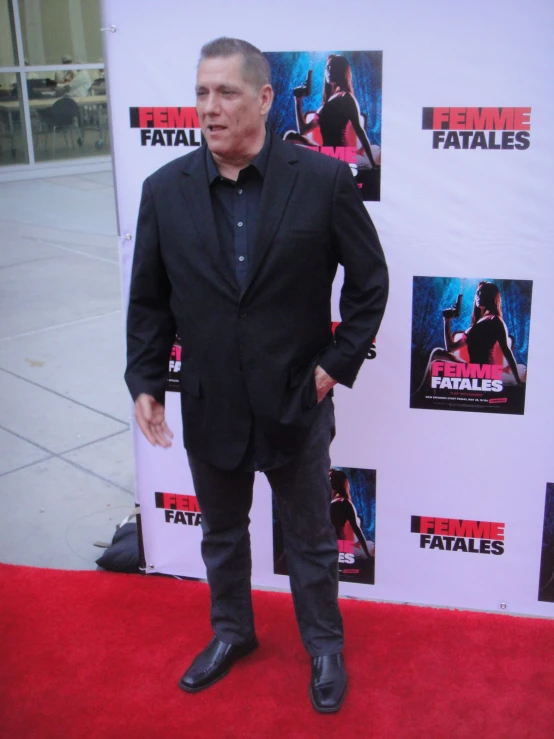 a man in a black suit poses on a red carpet