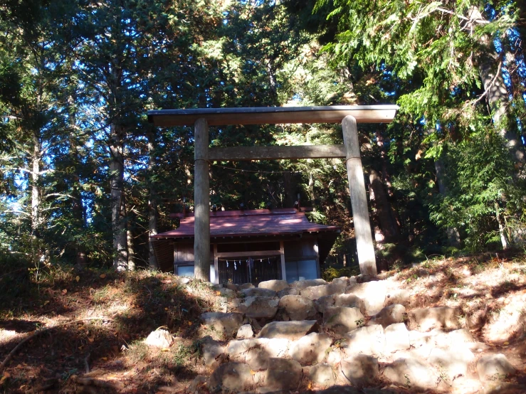 an arch stands next to trees on a rocky hillside