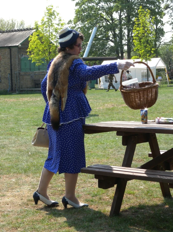 the woman is holding a basket near a picnic table