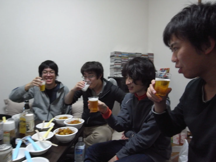 four asian people are drinking beer while eating food