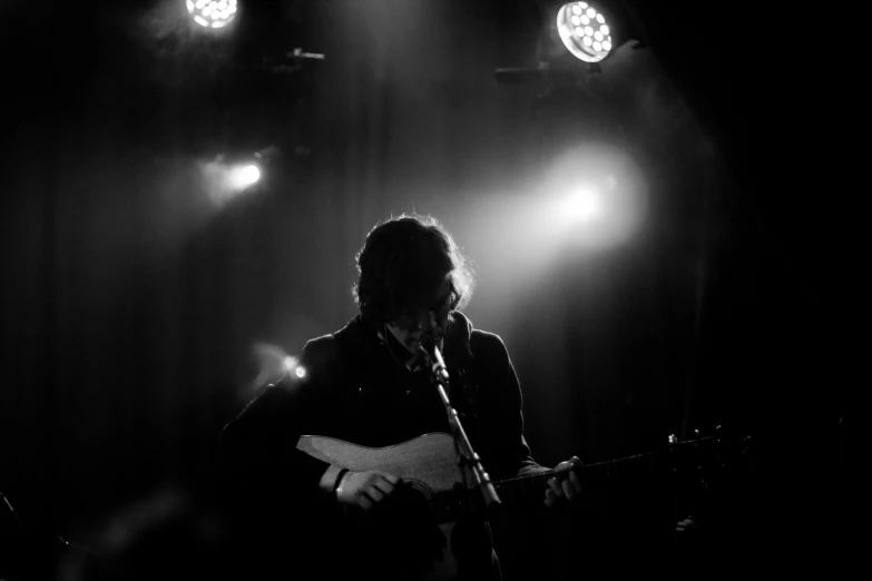 a man with a guitar sings into some lights