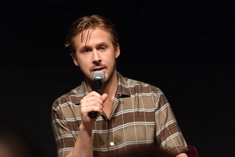 a man in a plaid shirt holds a microphone